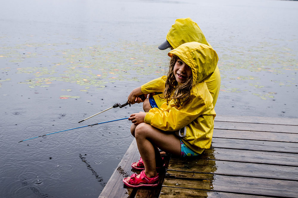 two children in yellow raincoats fishing off a dock